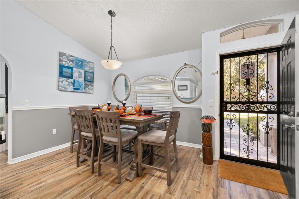 A dining room features a wooden table, six chairs, light gray walls, and a screen door — 428 BENT OAK LOOP, DAVENPORT, FL