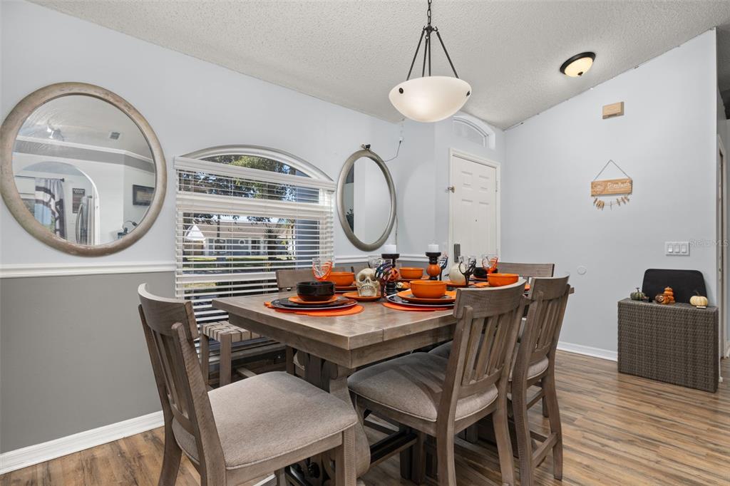 A dining room features a wooden table with orange place settings, chairs, and two mirrors — 428 BENT OAK LOOP, DAVENPORT, FL