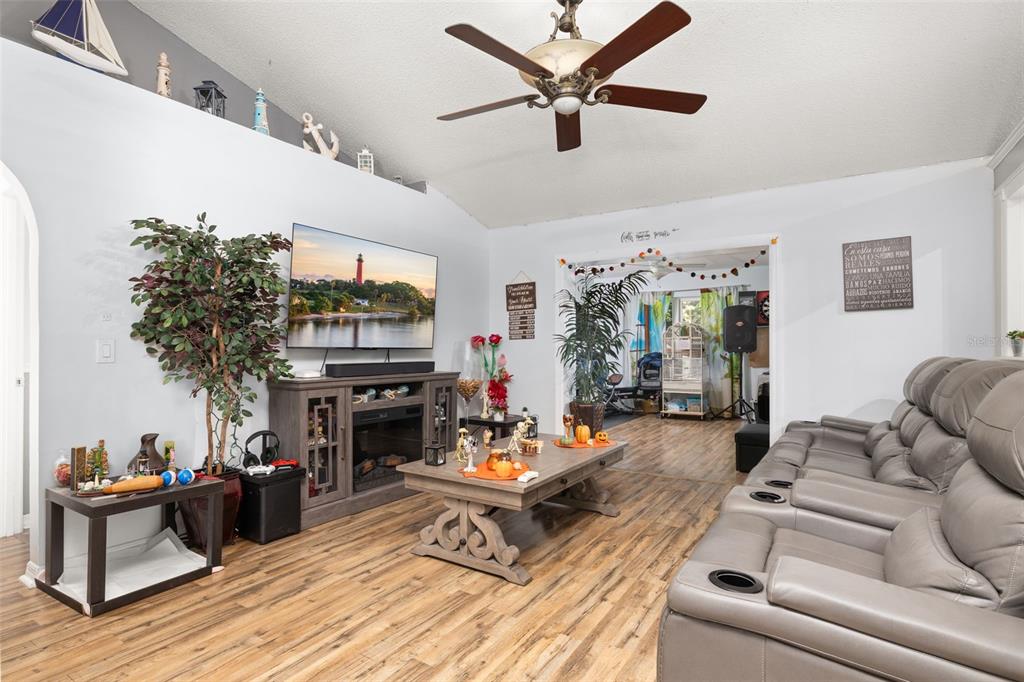A living room features a grey sectional sofa, a fireplace media console, and wood-look flooring — 428 BENT OAK LOOP, DAVENPORT, FL