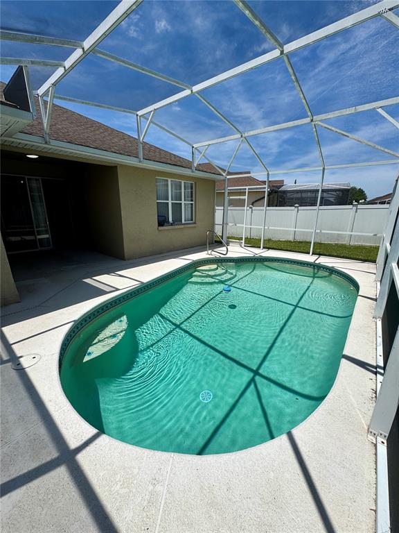 An oval swimming pool sits on a concrete patio enclosed by a screened-in lanai — 1671 ISLEBROOK DRIVE, ORLANDO, FL
