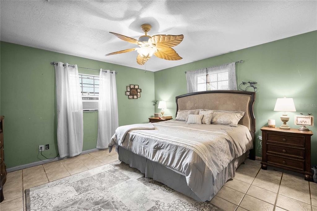 A bedroom with green walls, tile floors, a ceiling fan, and a large bed — 12237 CR 727, WEBSTER, FL