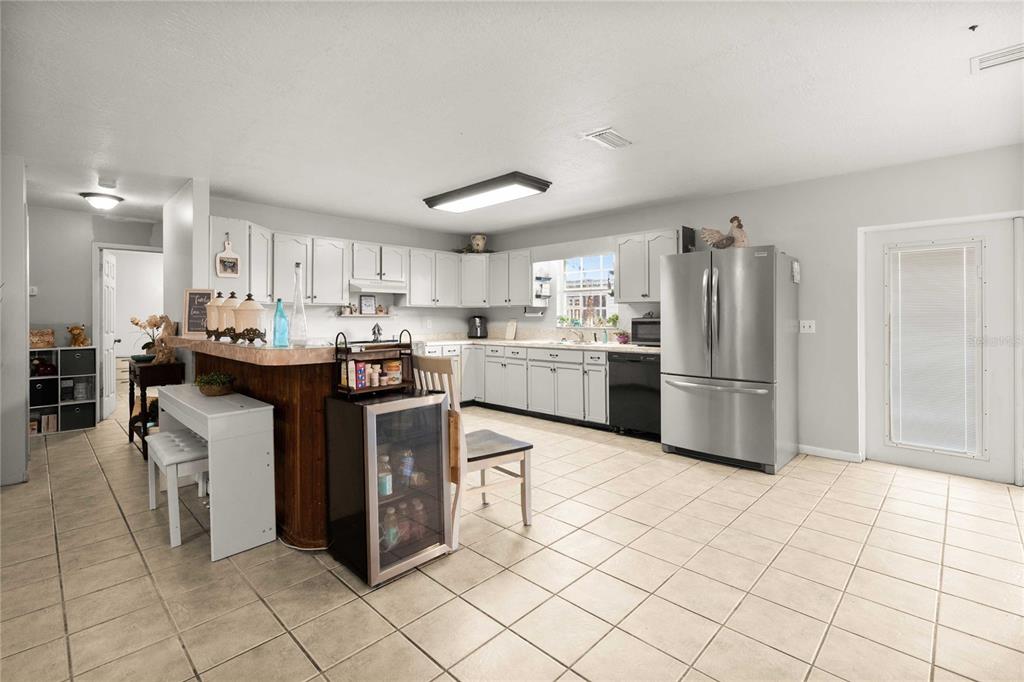 A kitchen with white cabinets, stainless steel appliances, a breakfast bar, and tile flooring — 12237 CR 727, WEBSTER, FL