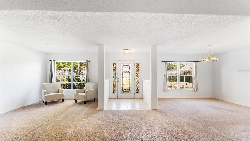A carpeted living area features a central entryway with a glass-paneled door and two chairs — 8 WHITE HURST LANE, PALM COAST, FL