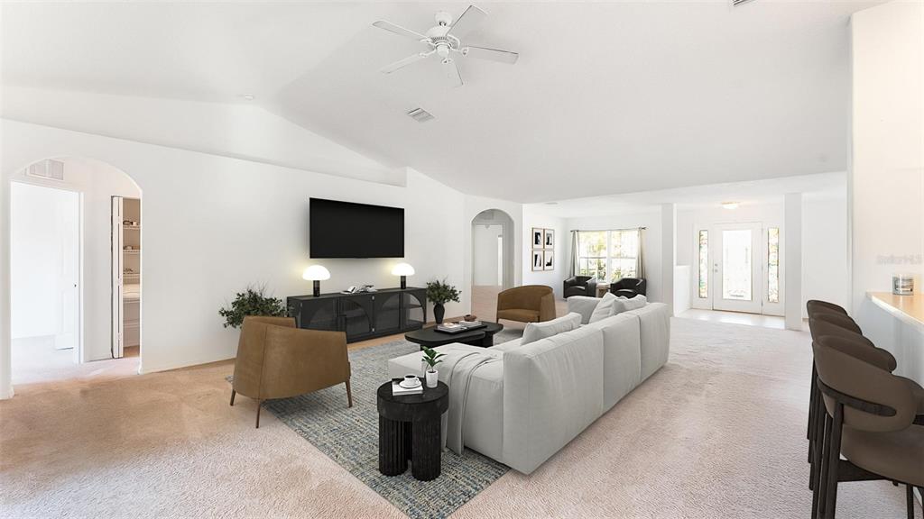 A spacious living room features a white sofa, brown armchairs, and a wall-mounted television — 8 WHITE HURST LANE, PALM COAST, FL