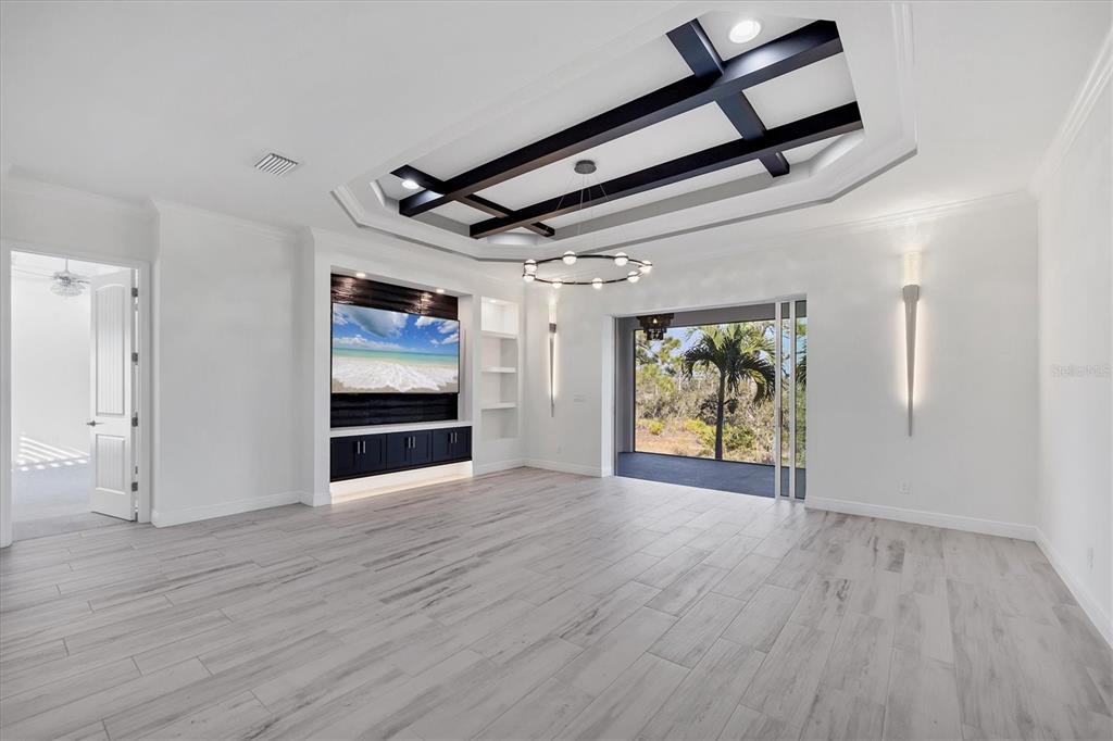 A modern living room features a coffered ceiling with dark beams, built-in cabinetry, and sliding doors — 8920 CONCH AVENUE, PLACIDA, FL
