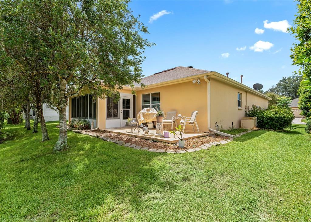 The exterior of a peach-colored house features a screened-in porch and a stone-bordered patio — 8368 SE 176TH LAWSON LOOP, THE VILLAGES, FL