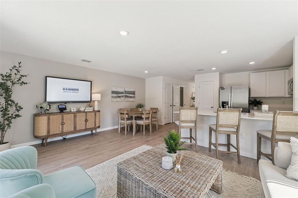 An open-concept living and dining area features light wood flooring, a kitchen island, and furniture — 717 PRESTON COVE DRIVE, ST CLOUD, FL
