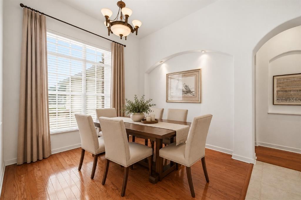 A dining room with hardwood floors, a chandelier, and a desk with two chairs — 5021 CHAMPIONSHIP CUP LANE, SPRING HILL, FL