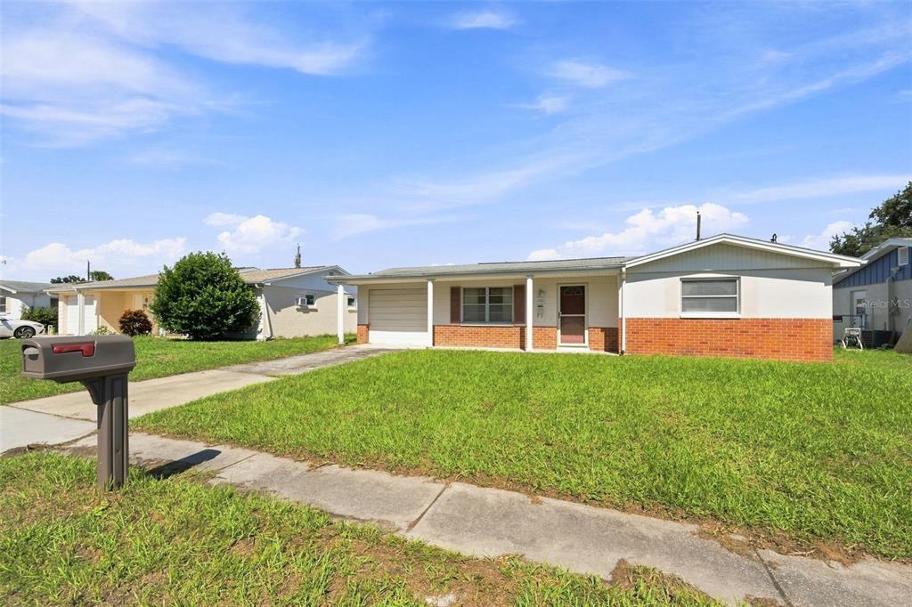 A single-story house with a brick facade, a front lawn, and an attached garage — 3420 BLAYTON STREET, HOLIDAY, FL