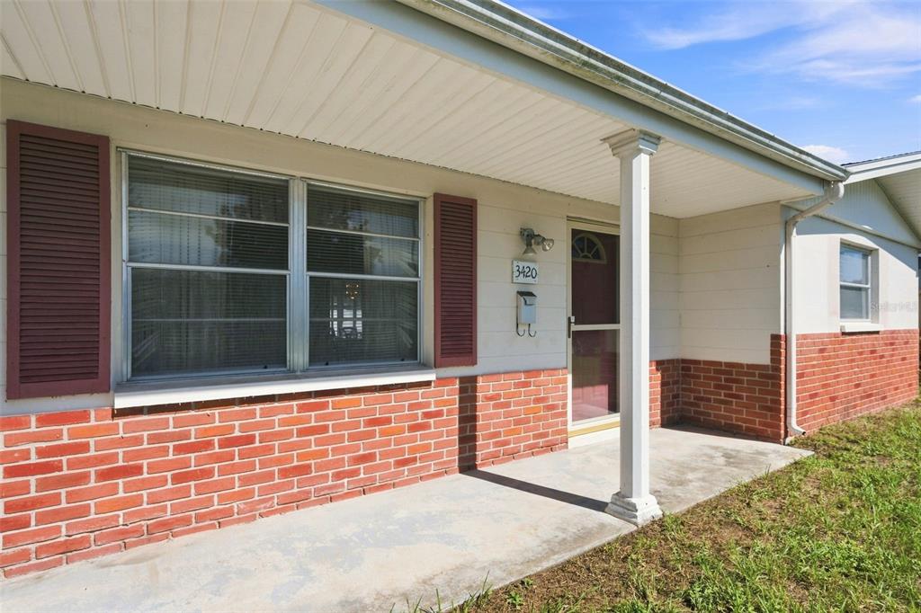 A front porch with a brick base, white siding, and a single support column — 3420 BLAYTON STREET, HOLIDAY, FL