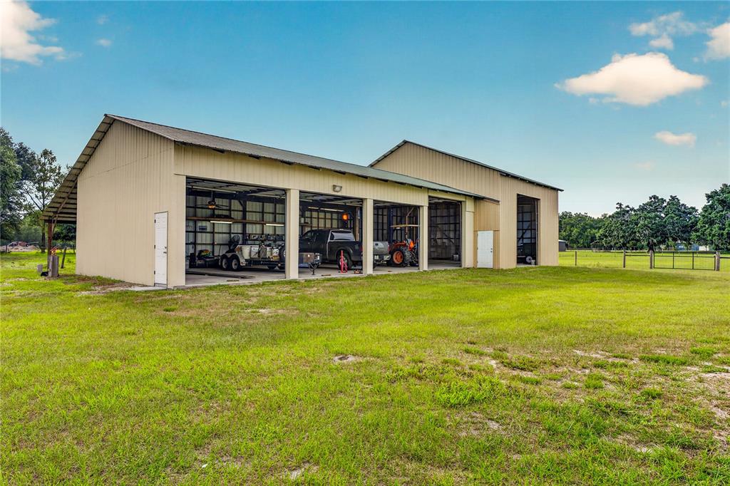 A beige detached garage with two white doors sits on a grassy rural lot — 2440 CR 546, BUSHNELL, FL