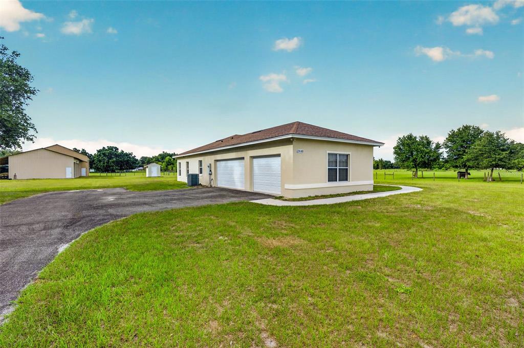 A living room features gray reclining sofas, a patterned area rug, and sliding glass doors — 2440 CR 546, BUSHNELL, FL