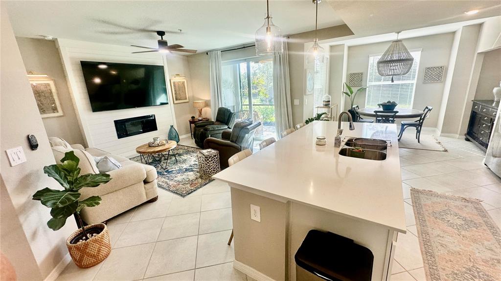An open-concept living room and kitchen feature a large island, fireplace, and dining area — 14221 HERITAGE LANDING UNIT 2013, PUNTA GORDA, FL