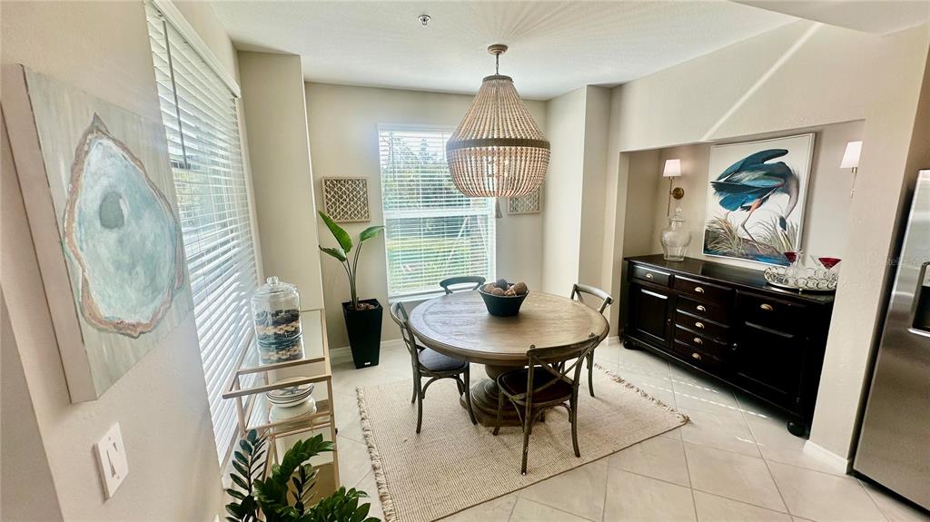 A dining room features a round wooden table, beaded chandelier, and a dark sideboard — 14221 HERITAGE LANDING UNIT 2013, PUNTA GORDA, FL