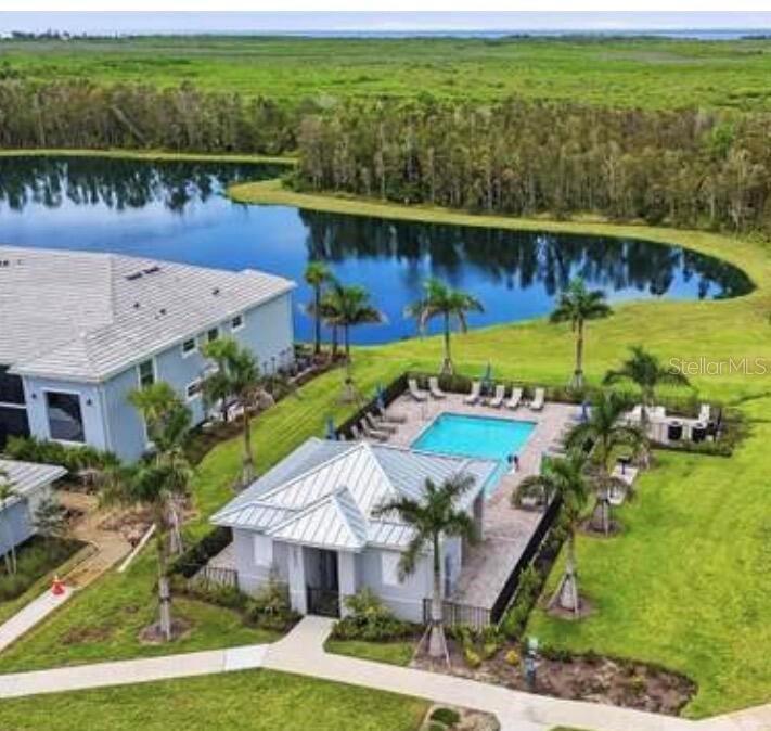 An aerial view shows a community swimming pool and clubhouse next to a large pond — 14221 HERITAGE LANDING UNIT 2013, PUNTA GORDA, FL