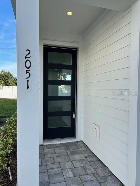 A modern dark-framed glass front door is set into a white horizontal-sided exterior wall — 2051 PEEL AVENUE, ORLANDO, FL