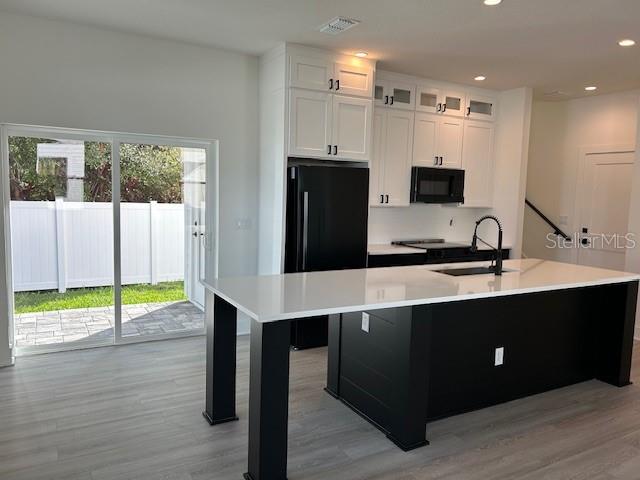 A modern kitchen features white upper cabinets, a black island, and a sliding glass door — 2051 PEEL AVENUE, ORLANDO, FL