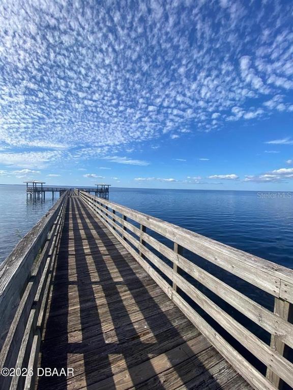 A long wooden pier extends over calm blue water under a bright, cloudy sky — 820 OLD BUBBLY ROAD, PIERSON, FL