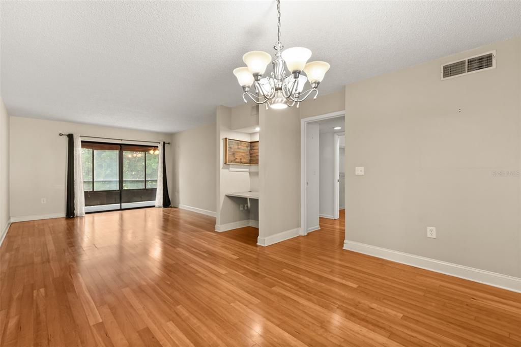 A living room with hardwood floors, a chandelier, and a built-in desk area — 4101 FAIRVIEW VISTA POINT UNIT 229, ORLANDO, FL