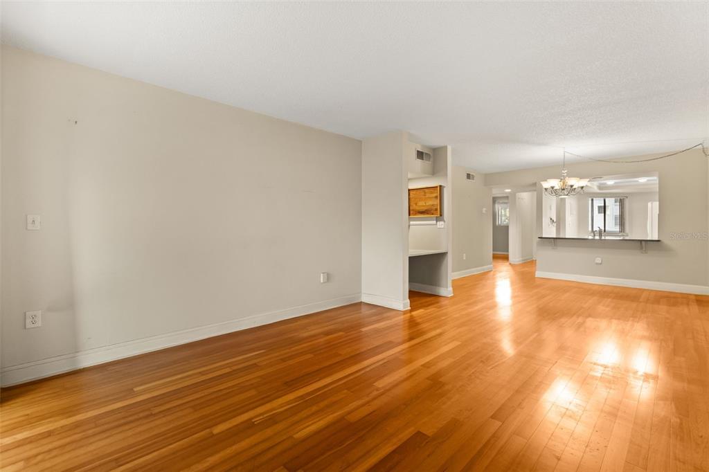 An empty room with light-colored walls and polished hardwood floors features a breakfast bar — 4101 FAIRVIEW VISTA POINT UNIT 229, ORLANDO, FL