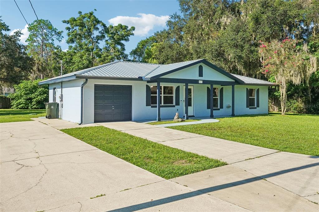 A single-story house with a light blue exterior, metal roof, and a concrete driveway — 417 W HUNT AVENUE, BUSHNELL, FL