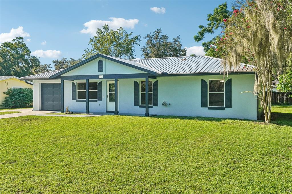 A single-story house with a metal roof, dark shutters, and a front porch — 417 W HUNT AVENUE, BUSHNELL, FL