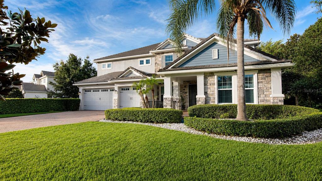 A two-story house with a stone and blue siding facade, a palm tree, and landscaping — 7467 LAKE ALBERT DRIVE, WINDERMERE, FL