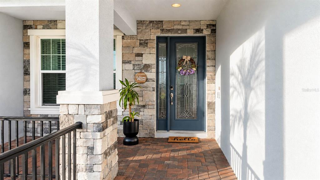 A front entryway features a blue glass-paneled door, stone veneer walls, and a brick porch — 7467 LAKE ALBERT DRIVE, WINDERMERE, FL