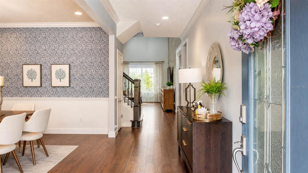 An entryway leads to a dining room with patterned wallpaper and dark wood flooring — 7467 LAKE ALBERT DRIVE, WINDERMERE, FL
