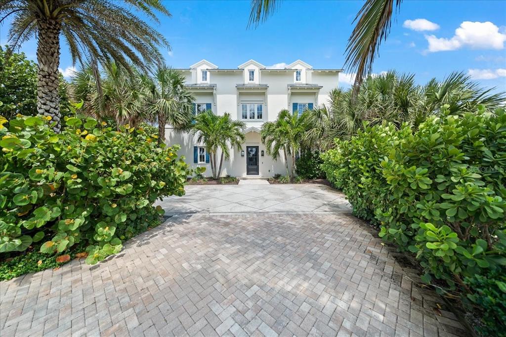 A three-story white house with blue shutters sits behind a paved driveway and landscaping — 5525 HIGHWAY A1A, MELBOURNE BEACH, FL