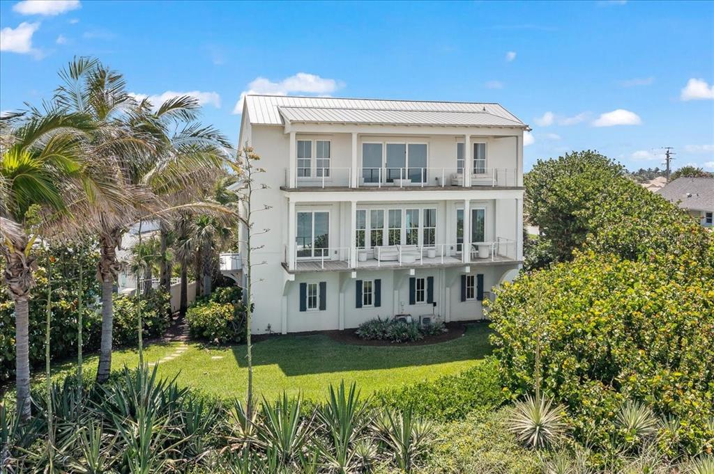 A three-story white house with balconies and large windows sits in a grassy yard — 5525 HIGHWAY A1A, MELBOURNE BEACH, FL