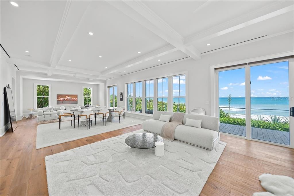 A bright, open-concept living and dining area features white coffered ceilings and ocean views — 5525 HIGHWAY A1A, MELBOURNE BEACH, FL