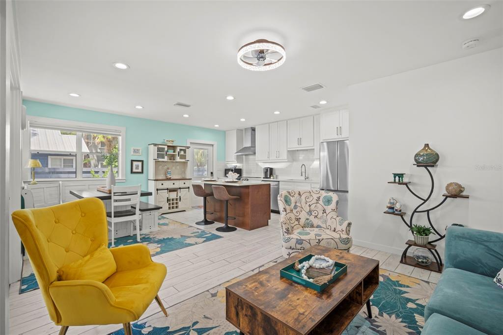 An open-concept living room and kitchen feature white cabinetry, a wood island, and colorful furniture — 1841 LAUREL STREET, SARASOTA, FL