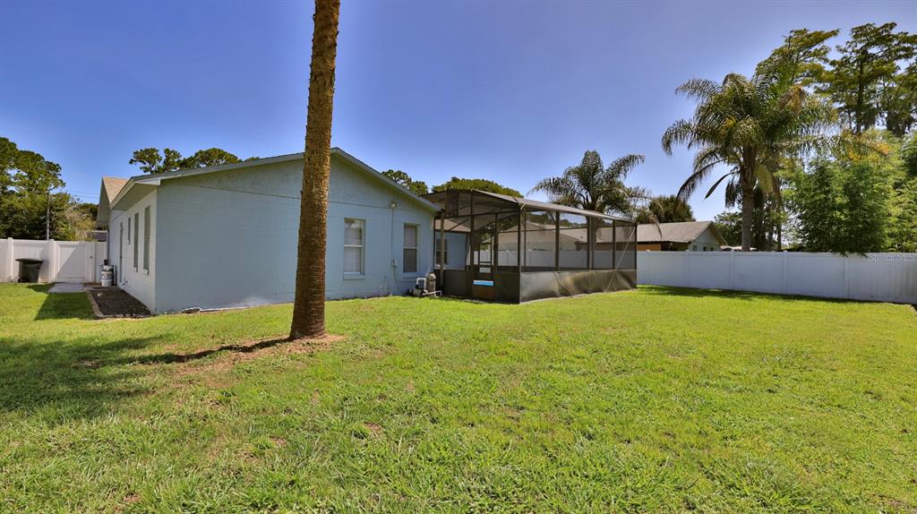 The exterior of a light blue house features a screened-in patio and a large backyard — 1404 N DEXTER DRIVE, PORT ORANGE, FL