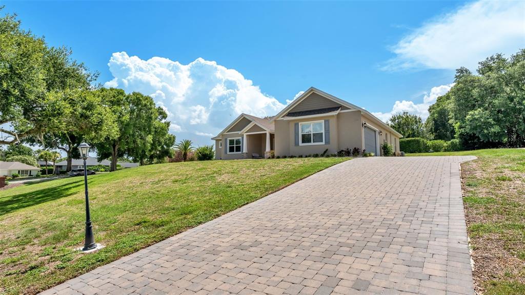 An aerial view shows a brick entrance sign for Grandview Village beside a grassy lot — 5701 CRESTVIEW DRIVE, LADY LAKE, FL