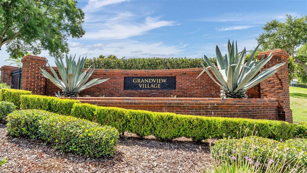 A brick entrance sign for Grandview Village features two large agave plants and manicured hedges — 5701 CRESTVIEW DRIVE, LADY LAKE, FL