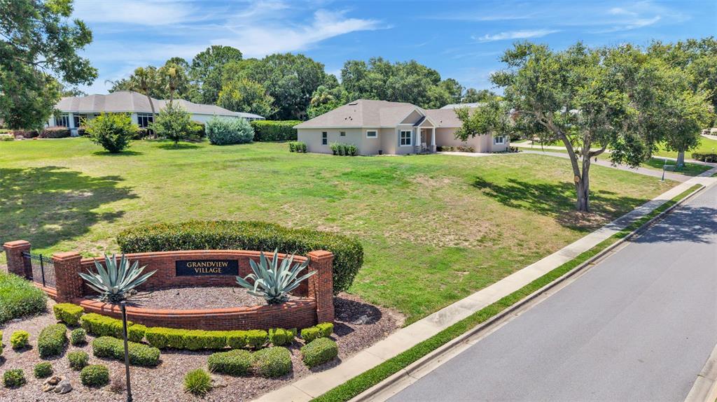 A brick entrance sign for Grandview Village features two large agave plants and manicured hedges — 5701 CRESTVIEW DRIVE, LADY LAKE, FL