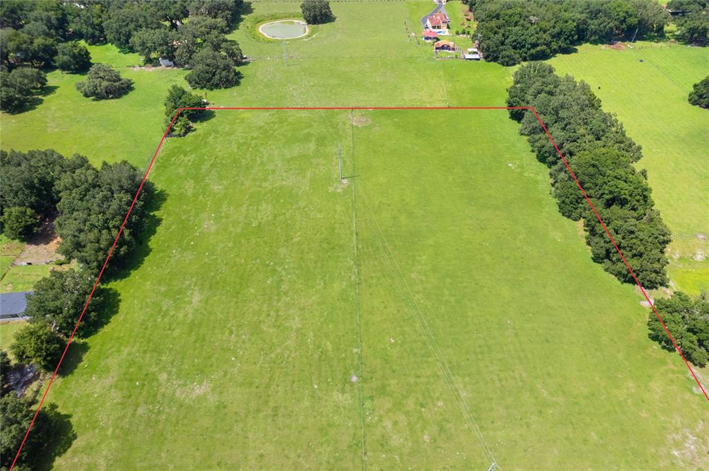 An aerial view shows a large, rectangular grassy field outlined in red — CR 552, BUSHNELL, FL