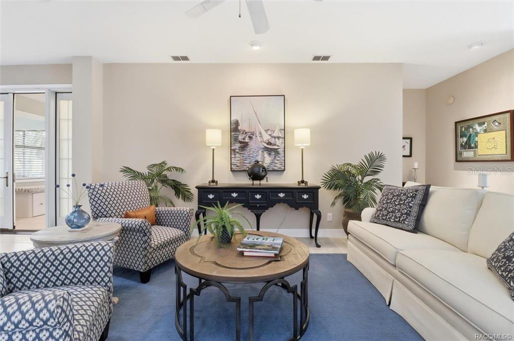 A living room features a blue rug, a white sofa, patterned armchairs, and a console table — 3351 N HIDDEN VALLEY POINT, LECANTO, FL