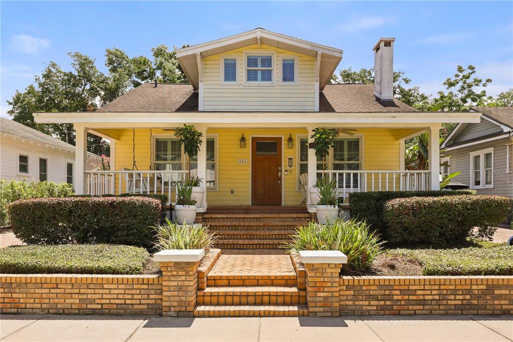 A yellow bungalow with a front porch, brick retaining wall, and a paved driveway — 343 BROADWAY AVENUE, ORLANDO, FL