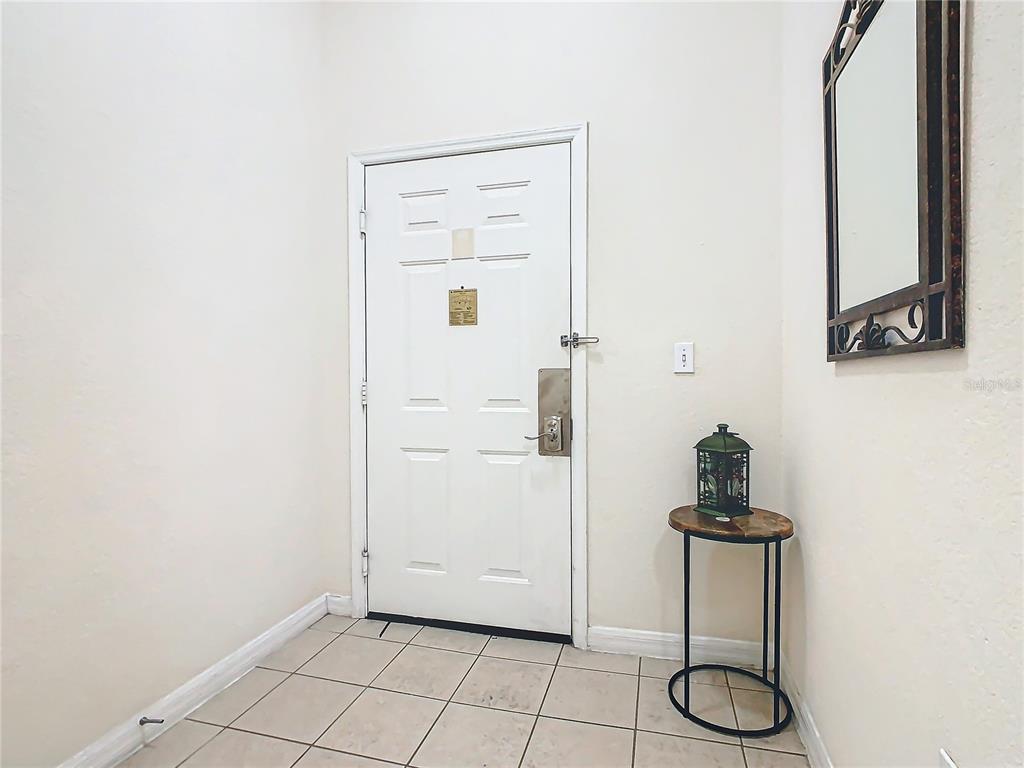 A white front door opens into a tiled entryway with a small side table — 3050 PIRATES RETREAT COURT UNIT 108, KISSIMMEE, FL