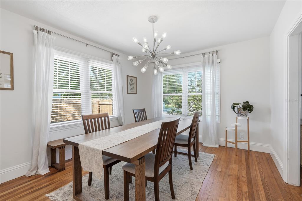 A dining room features a wooden table, chairs, a bench, and a modern sputnik chandelier — 6031 HOBSON STREET NE, ST PETERSBURG, FL