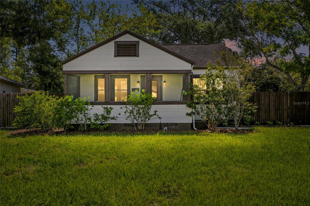 A single-story house with a screened-in front porch sits behind a green lawn at dusk — 6031 HOBSON STREET NE, ST PETERSBURG, FL