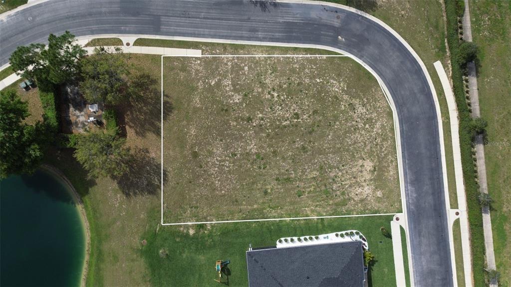 An aerial view shows a vacant, rectangular residential lot bordered by a curved street — 760 WATER FERN TRAIL DRIVE, AUBURNDALE, FL