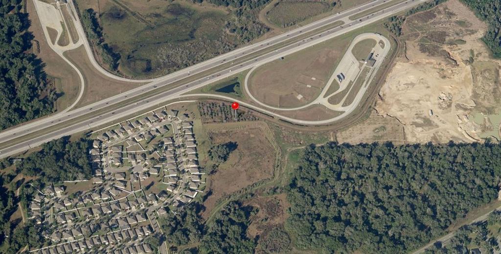 This aerial view shows a residential neighborhood, a highway interchange, and a vacant wooded lot — ZZZ | UNPLATTED, SEFFNER, FL