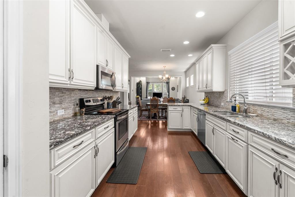 A kitchen with white cabinets, granite countertops, stainless steel appliances, and hardwood floors — 8317 SW 78TH LANE, GAINESVILLE, FL