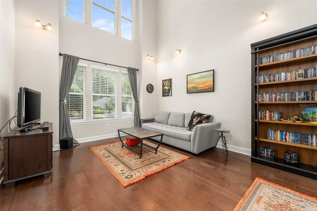 A living room features high ceilings, hardwood floors, a grey sofa, and a large bookshelf — 8317 SW 78TH LANE, GAINESVILLE, FL