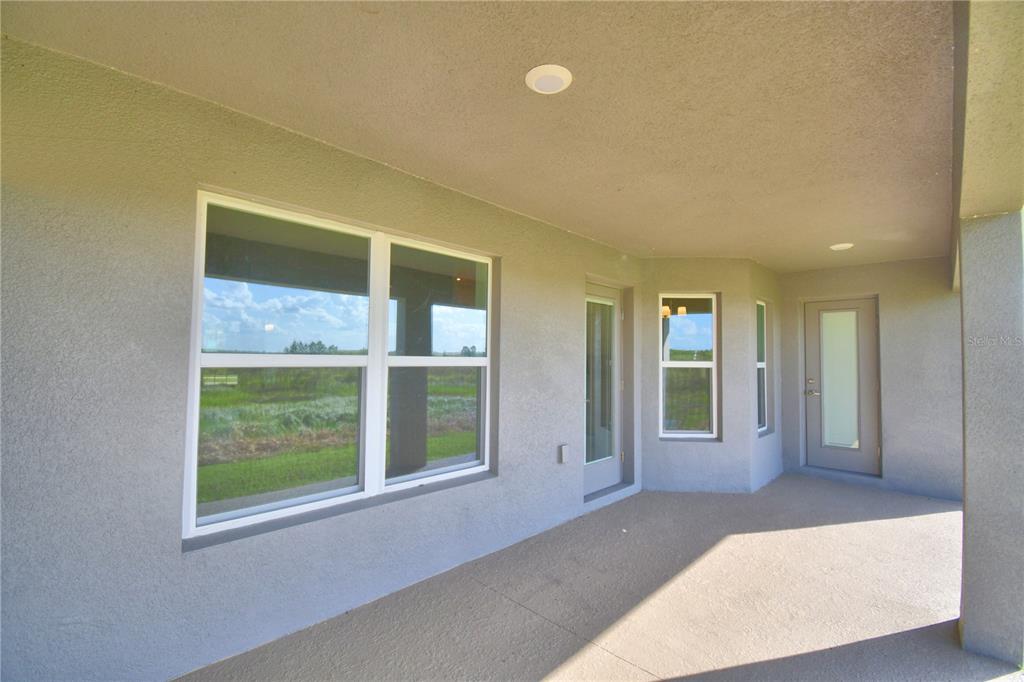 A covered concrete patio features stucco walls, recessed lighting, and multiple windows and doors — 4645 CALAMINT LANE, AUBURNDALE, FL