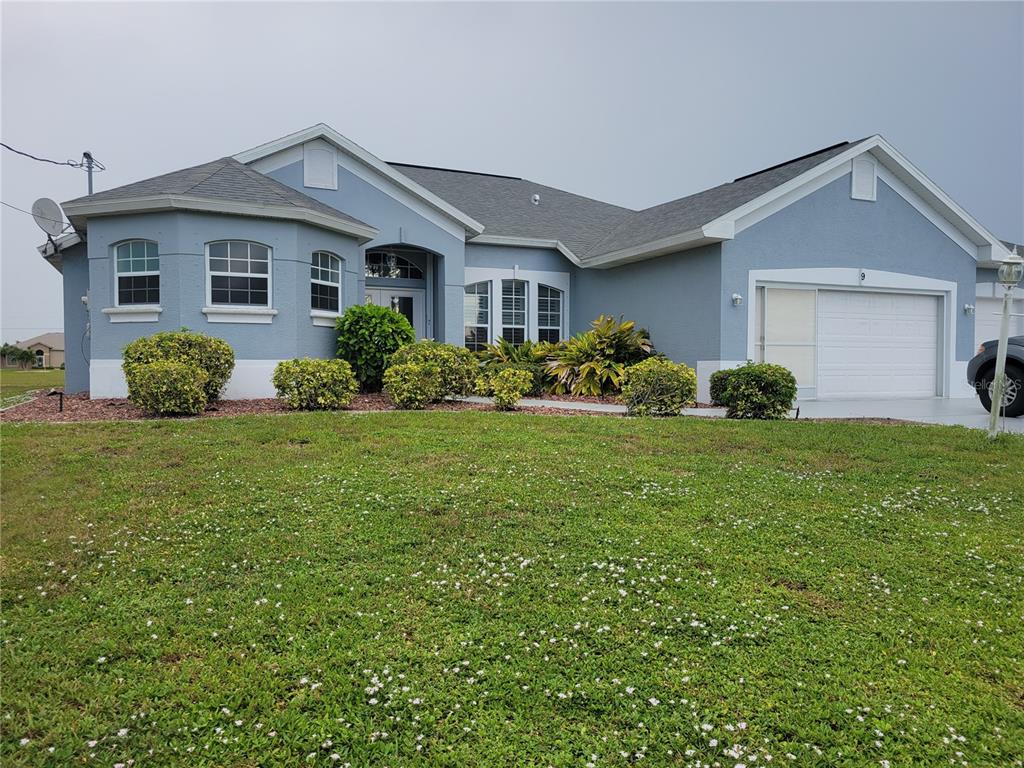 A single-story blue house with a white garage and a grassy front yard — 9 BUNKER TERRACE, ROTONDA WEST, FL