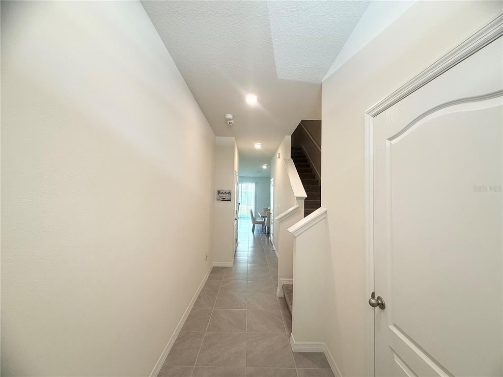 A tiled entryway leads to a hallway with a staircase and a view of dining — 1503 ISLETA LOOP, KISSIMMEE, FL